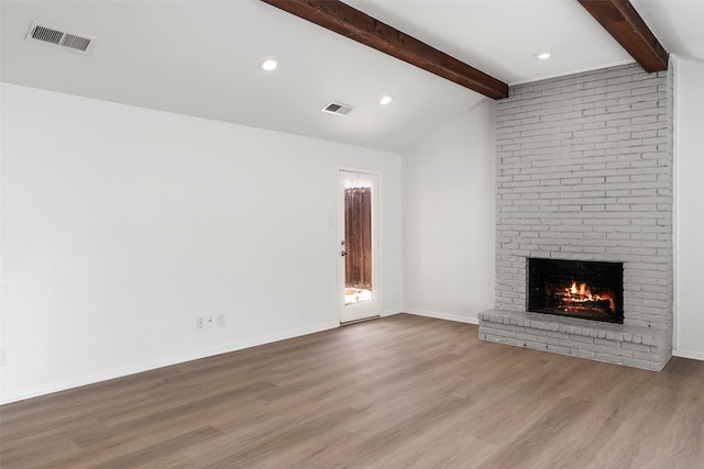 unfurnished living room featuring lofted ceiling with beams, light hardwood / wood-style floors, and a brick fireplace