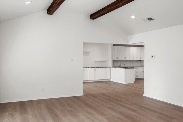 unfurnished living room with vaulted ceiling with beams, sink, and light hardwood / wood-style flooring