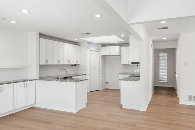 kitchen featuring stone counters, light hardwood / wood-style floors, and white cabinetry