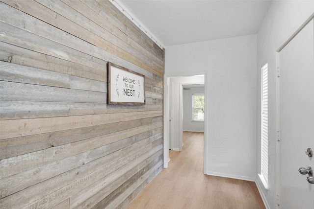 hallway featuring light hardwood / wood-style floors and wooden walls