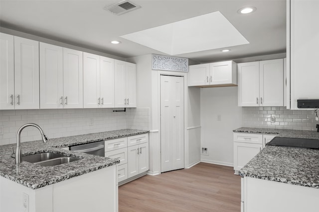 kitchen with light wood-type flooring, white cabinetry, and dark stone counters