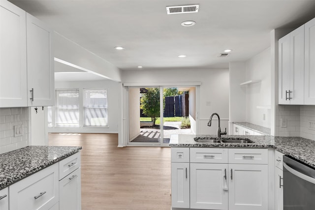 kitchen featuring dishwasher, dark stone counters, white cabinets, sink, and light hardwood / wood-style flooring