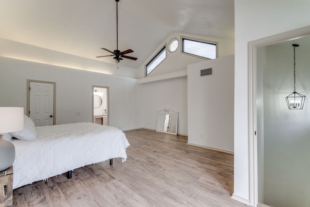 bedroom featuring ceiling fan, light wood-type flooring, high vaulted ceiling, and ensuite bath