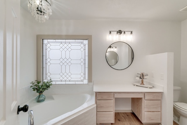 bathroom with hardwood / wood-style floors, vanity, an inviting chandelier, toilet, and tiled bath