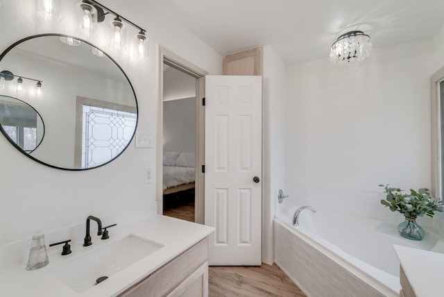 bathroom with tiled bath, vanity, wood-type flooring, and a notable chandelier