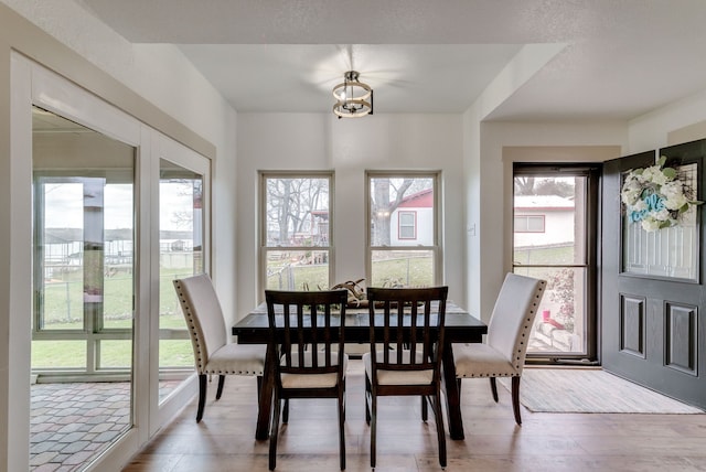 dining space featuring light hardwood / wood-style flooring, a textured ceiling, and a notable chandelier