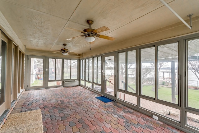 unfurnished sunroom with ceiling fan and a wall mounted air conditioner