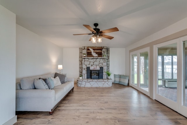 living room with light wood-type flooring, a wood stove, and ceiling fan