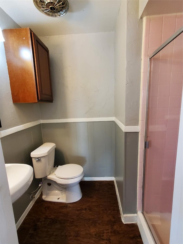 bathroom featuring wood-type flooring, toilet, and a shower with door