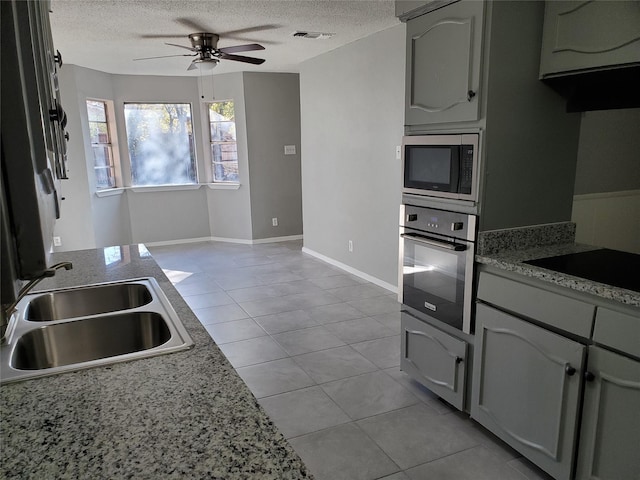 kitchen featuring appliances with stainless steel finishes, a textured ceiling, ceiling fan, sink, and light tile patterned flooring