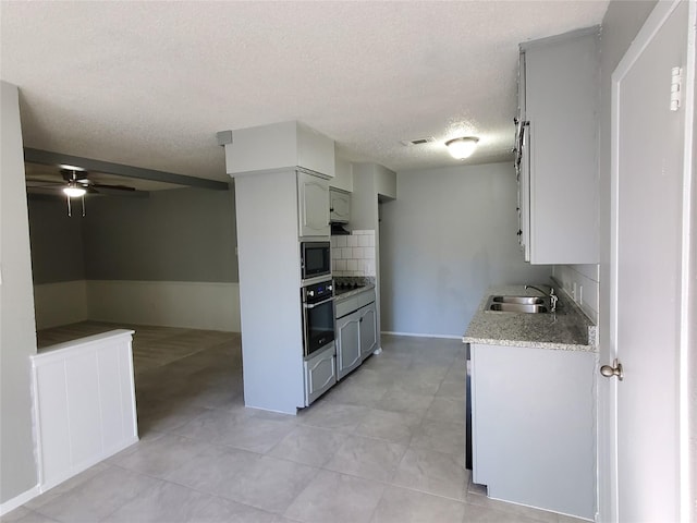 kitchen featuring sink, ceiling fan, a textured ceiling, tasteful backsplash, and stainless steel appliances