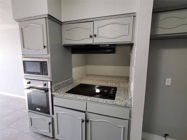 kitchen with light stone countertops, appliances with stainless steel finishes, and light tile patterned floors