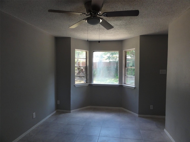 tiled empty room with ceiling fan and a textured ceiling