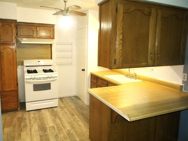 kitchen with gas range gas stove, sink, light hardwood / wood-style flooring, kitchen peninsula, and a kitchen bar