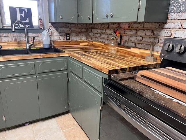 kitchen featuring wood counters, sink, green cabinetry, light tile patterned floors, and black range with electric cooktop