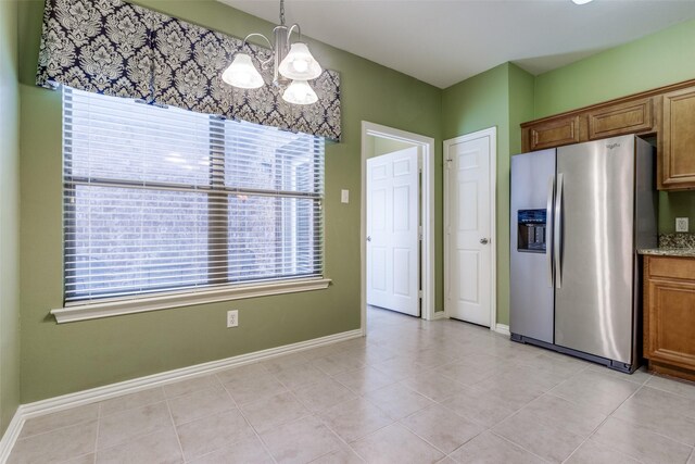 kitchen featuring light stone countertops, light tile patterned floors, pendant lighting, a chandelier, and stainless steel fridge with ice dispenser