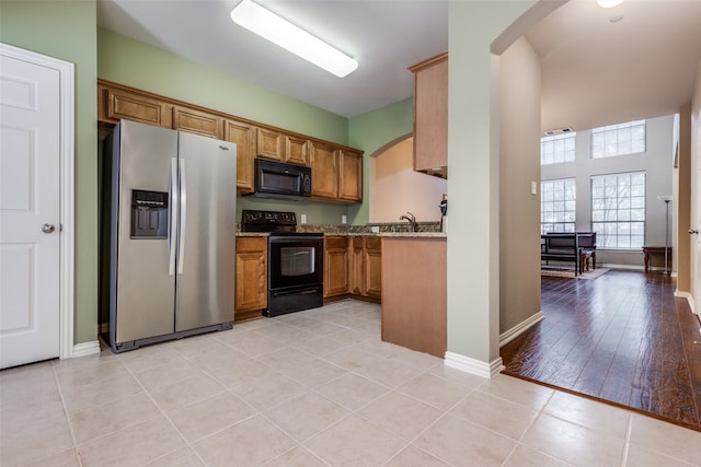 kitchen featuring light stone countertops, black appliances, and light hardwood / wood-style floors