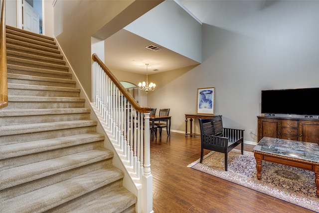 stairway with hardwood / wood-style floors and an inviting chandelier