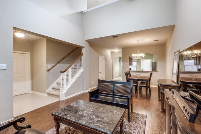 living room with hardwood / wood-style floors, a towering ceiling, and a notable chandelier