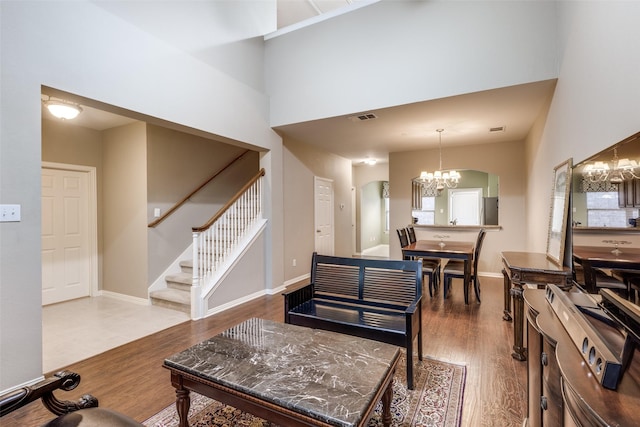 living room with hardwood / wood-style floors, a towering ceiling, and a notable chandelier