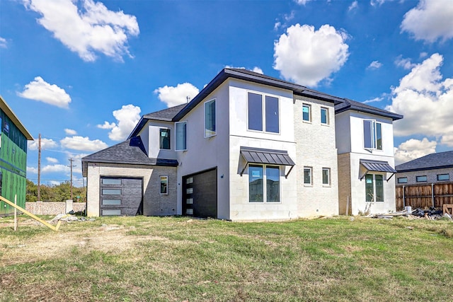 rear view of property featuring a lawn and a garage