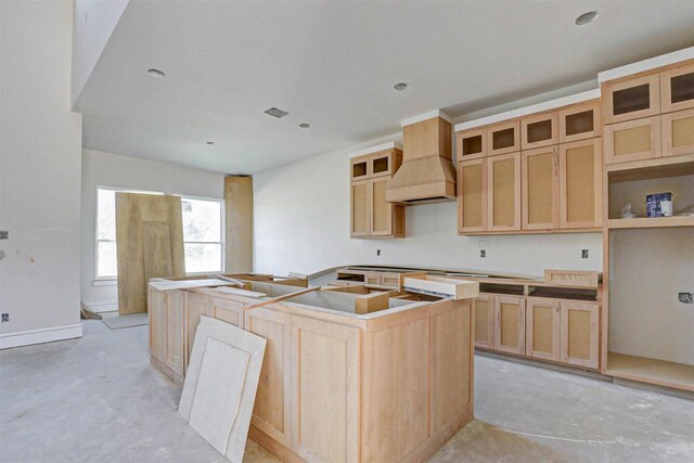 kitchen with light brown cabinets, a center island, and premium range hood