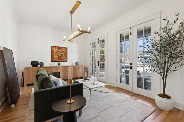 living area featuring french doors, a notable chandelier, crown molding, and wood finished floors