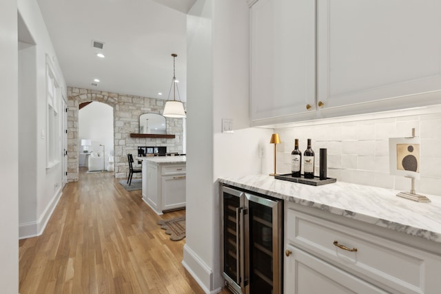 bar with wine cooler, white cabinetry, pendant lighting, light hardwood / wood-style floors, and decorative backsplash