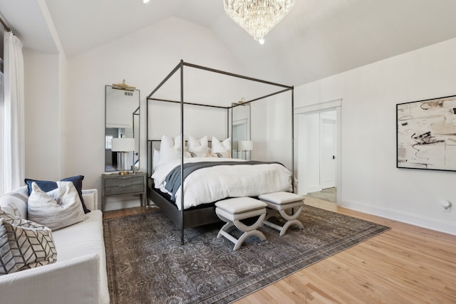 bedroom featuring hardwood / wood-style flooring, lofted ceiling, an inviting chandelier, and a closet