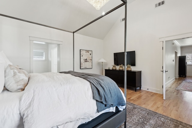 bedroom with wood-type flooring, vaulted ceiling, a chandelier, and a closet