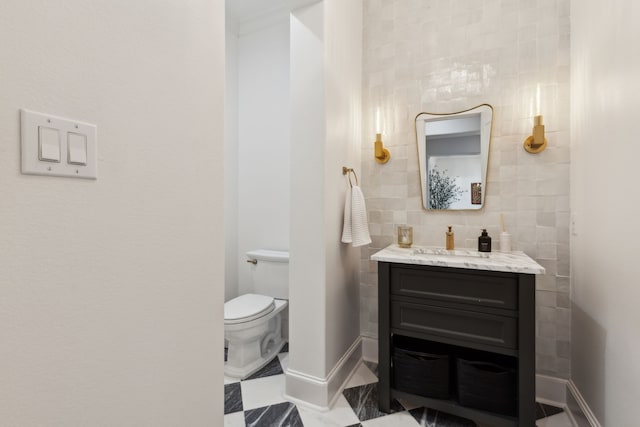 bathroom featuring vanity, toilet, and tile walls