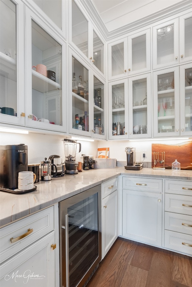 bar with white cabinets, dark hardwood / wood-style floors, light stone counters, and beverage cooler