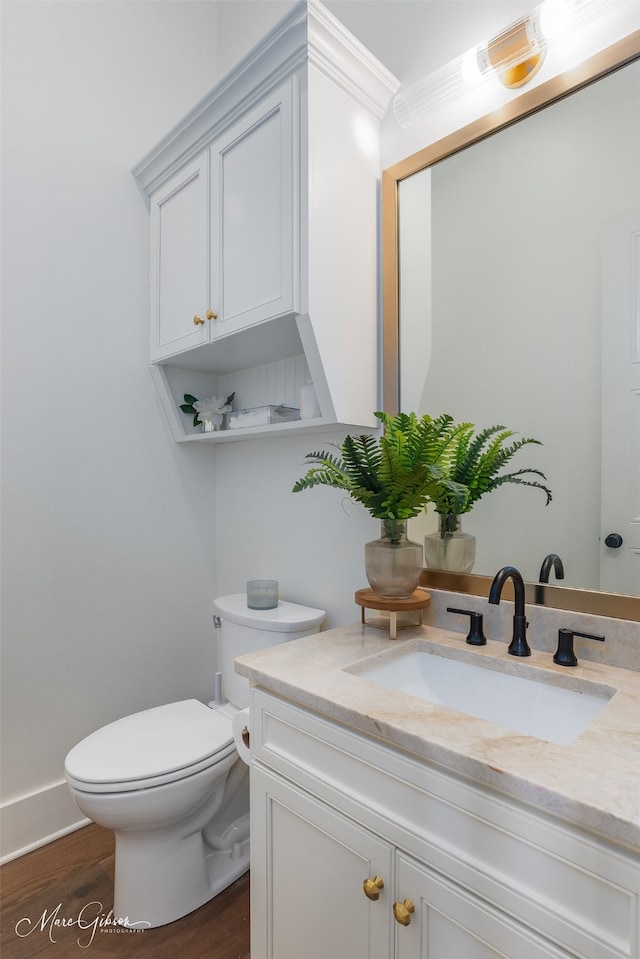 bathroom featuring hardwood / wood-style floors, vanity, toilet, and ornamental molding