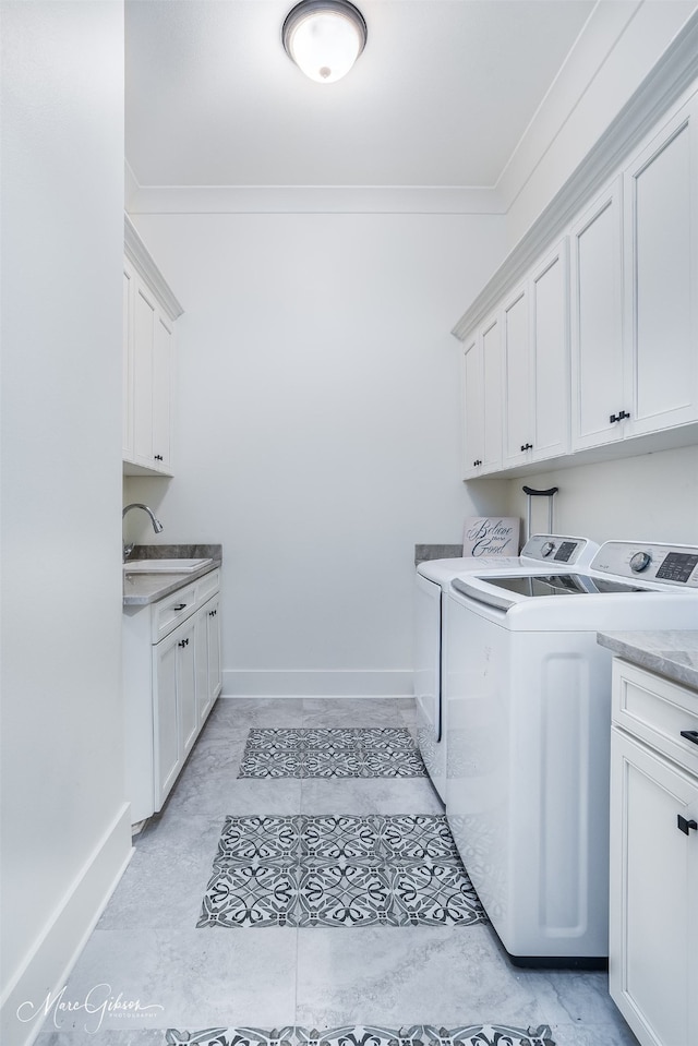 laundry room featuring washing machine and clothes dryer, sink, cabinets, and ornamental molding