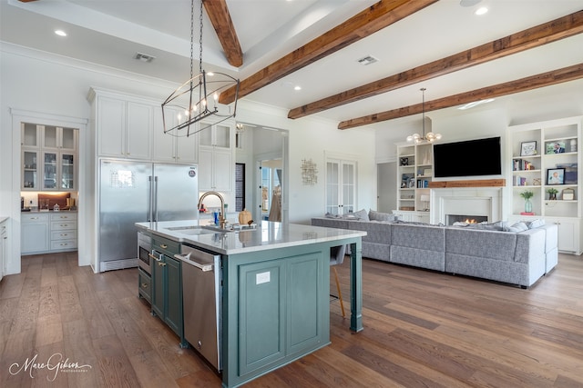 kitchen with sink, beam ceiling, pendant lighting, a center island with sink, and white cabinetry