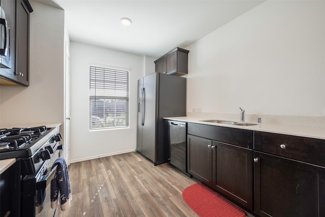 kitchen with dark brown cabinetry, light wood-type flooring, sink, and appliances with stainless steel finishes