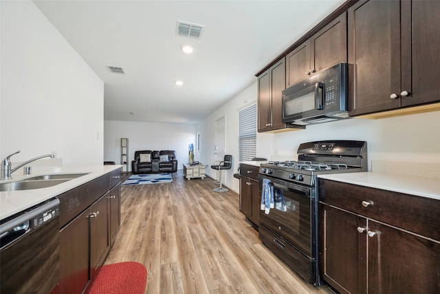 kitchen with black appliances, dark brown cabinets, sink, and light hardwood / wood-style flooring