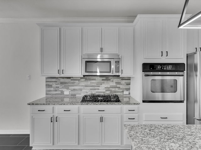 kitchen featuring white cabinets, light stone counters, stainless steel appliances, and tasteful backsplash