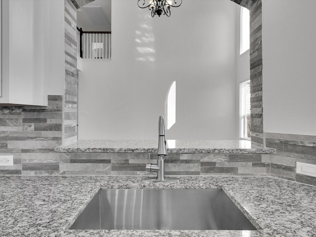 kitchen with a notable chandelier, light stone countertops, and sink