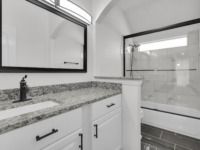 full bathroom with vanity, toilet, lofted ceiling, and bath / shower combo with glass door