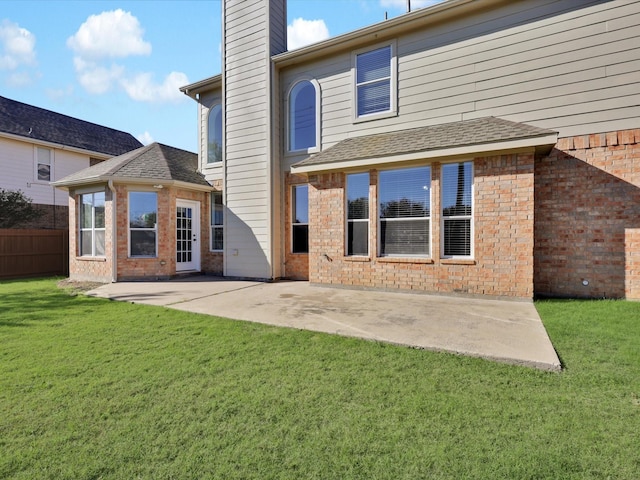 back of property with a yard and a patio