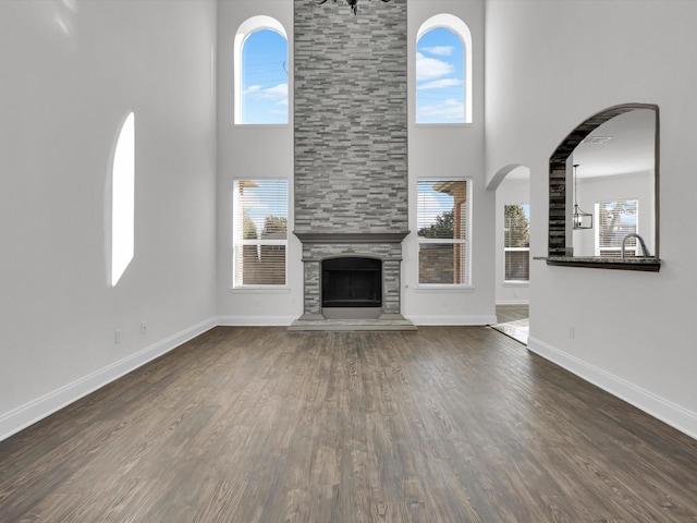 unfurnished living room featuring dark hardwood / wood-style flooring, a fireplace, and a towering ceiling