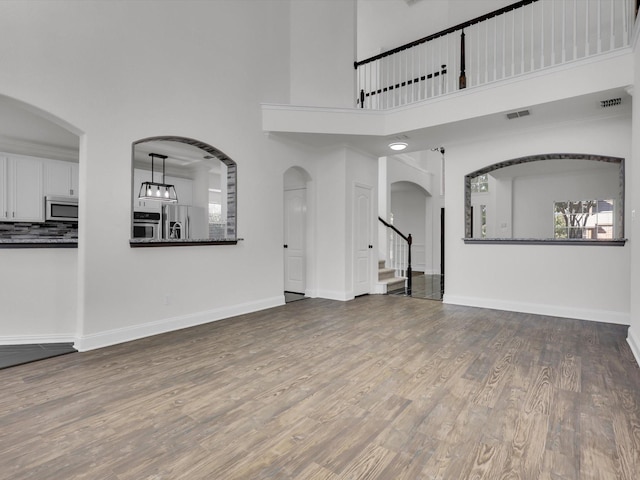 unfurnished living room featuring dark hardwood / wood-style flooring and a towering ceiling