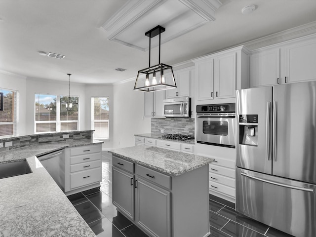 kitchen with light stone counters, white cabinetry, stainless steel appliances, and hanging light fixtures