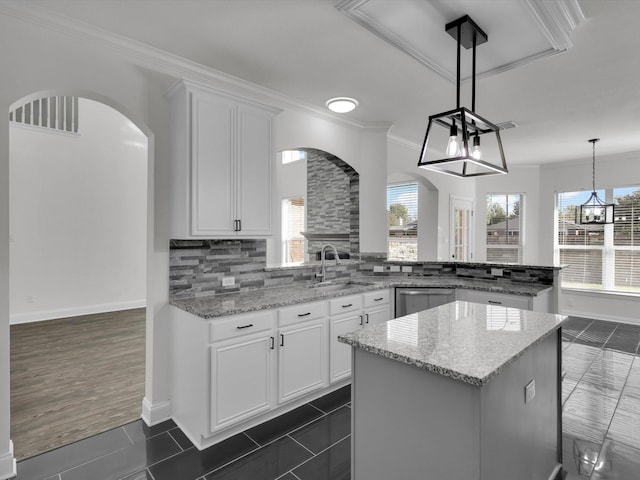 kitchen with backsplash, light stone countertops, white cabinets, and hanging light fixtures