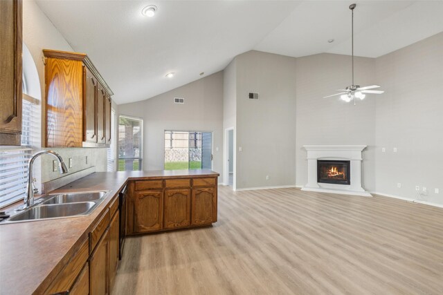 kitchen featuring kitchen peninsula, sink, black appliances, high vaulted ceiling, and light hardwood / wood-style floors