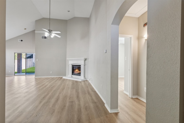 unfurnished living room with ceiling fan, high vaulted ceiling, and light wood-type flooring