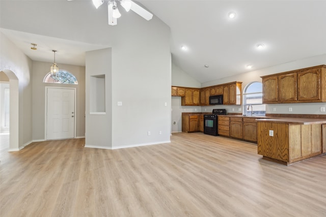 kitchen with black appliances, a healthy amount of sunlight, light hardwood / wood-style floors, and high vaulted ceiling