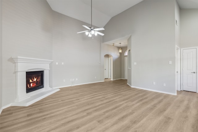 unfurnished living room featuring ceiling fan, high vaulted ceiling, and light wood-type flooring