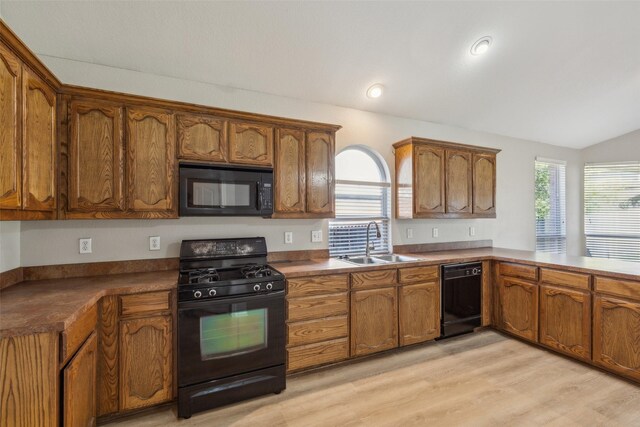 kitchen with sink, light hardwood / wood-style flooring, high vaulted ceiling, kitchen peninsula, and black appliances